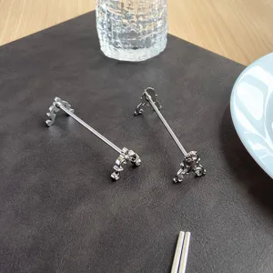 Close-up view of vintage carved silver stainless steel chopstick rest on a dark textured mat