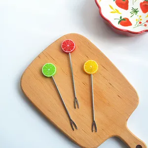 Stainless steel fruit forks set with cute citrus slice handles on wood board detail