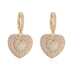 Close-up of gold huggie earrings with double-layered pink and clear heart charms