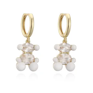 Détail de boucles d'oreilles ours avec des pierres claires et une finition en émail blanc.