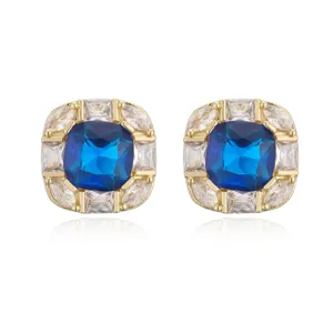 Macro view of 18K gold plated square earrings featuring a large blue gemstone and pavé halo