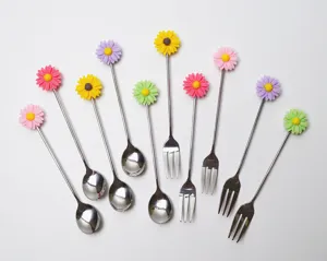 Détail des fourchettes à dessert et cuillères à café en inox avec fleurs de marguerite