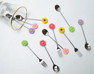Détail rapproché de cuillères et fourchettes à dessert en inox à motif marguerite