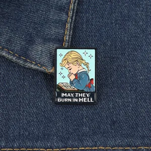 Détail macro d'un pin's en émail humoristique fille en prière sur tissu en denim