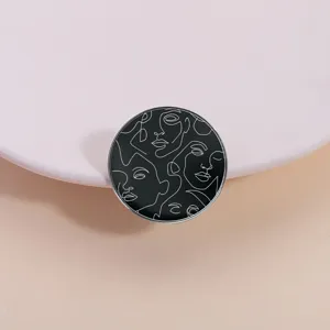 Spilla rotonda minimalista in metallo nero con volti astratti a linee bianche