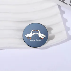 Funny circular metal brooch featuring a white geese wing-bump illustration and text
