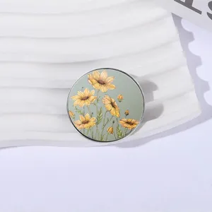 Round metal sunflower brooch pin with floral illustration on sage green background