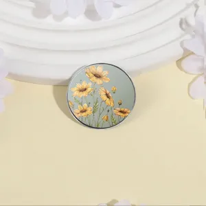 Round metal sunflower brooch pin with yellow floral illustration on sage green base