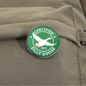 Detail of funny 'Certified Silly Goose' flying white goose enamel pin on khaki.
