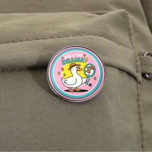 Funny cartoon duck metal brooch badge with 'Am I the drama' text on a backpack