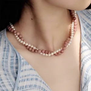 Primo piano di una collana a due strati con perle bianche e pietre rosa su modella
