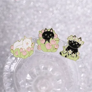 Detail view of three cute enamel cat pins with tulip and daisy floral designs