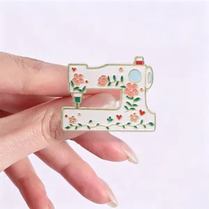 Close-up detail of a vintage sewing machine enamel pin with colorful floral patterns.