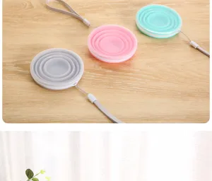 Detailed view of portable silicone folding cups in various colors with lanyards on wood