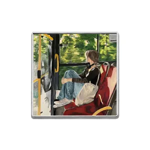 Detail of square metal badge featuring an artistic illustration of a girl on a bus