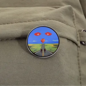 Detail van surrealistische ronde metalen speld op een kaki gekleurde rugzak