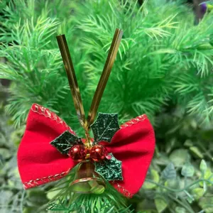 Dettaglio del fiocco di Natale in velluto rosso con campanellino d'oro e foglie verdi
