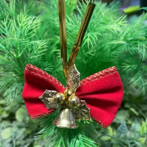 Dettaglio fiocco di Natale in velluto rosso con campanella dorata e agrifoglio