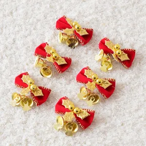 Scatto dettagliato di fiocchi natalizi in velluto rosso con campanelle e foglie dorate