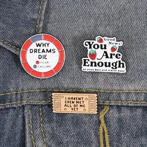 Detailansicht von drei motivierenden Emaille-Pins mit Slogans auf Denim-Hintergrund.