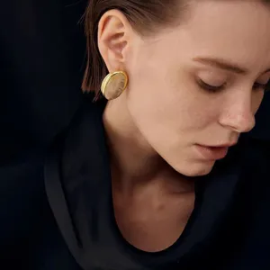 Elegante primer plano de una modelo con pendientes ovales bañados en oro con cuarzo ahumado