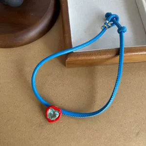 Stylish blue leather cord necklace featuring a red heart pendant with crystal center