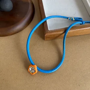 Detailed view of blue leather cord necklace with orange flower pendant and crystal