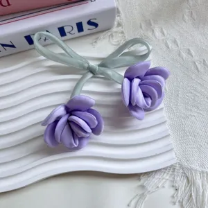 Dettaglio accessorio floreale rosa satin viola con nastro verde su vassoio bianco