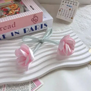 Dettaglio di accessori a forma di rosa in tessuto rosa con nastro verde