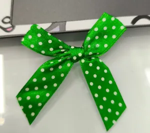 Détail d'un nœud en ruban de satin vert fait main avec d'élégants pois blancs.