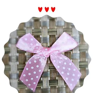 Vue détaillée d'un nœud en satin rose fait main avec des pois blancs pour cadeaux