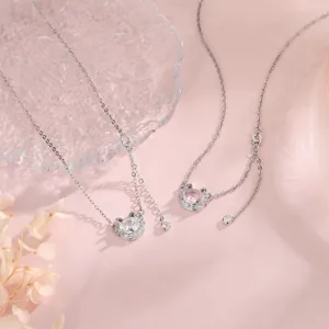 Vista detallada de collares de gato de circón con piedras rosas y claras en fondo rosa