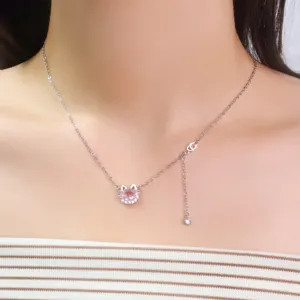 Primer plano de un collar de plata con un colgante de gato con circón rosa brillante