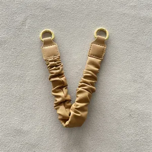 Nahaufnahme einer khakifarbenen Leder-Handgelenkschlaufe mit goldenen Metallringen