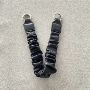 Detailansicht eines schwarzen, gefalteten Leder-Handygurts mit hochwertigen Silberringen.