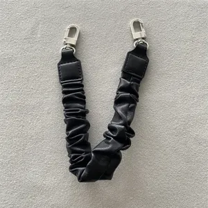 Detailansicht einer schwarzen, plissierten Leder-Telefonhandschlaufe mit Silberkarabiner