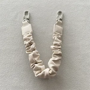 Nahaufnahme eines cremefarbenen PU-Leder-Handgelenkriemens für Handys mit silbernen Clips