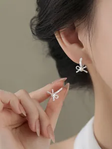 Detailed macro view of elegant silver bow-knot earrings with sparkling zircon and pearls.