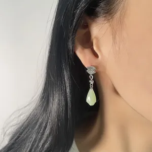 Close-up of elegant fan-shaped earrings with pale green jade-style drop pendant.