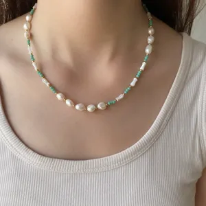 Vue détaillée d'un collier de perles vert menthe avec perles baroques sur un mannequin.