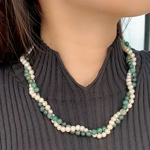 Dettaglio di una collana a doppio strato intrecciata con perle bianche e grani verdi