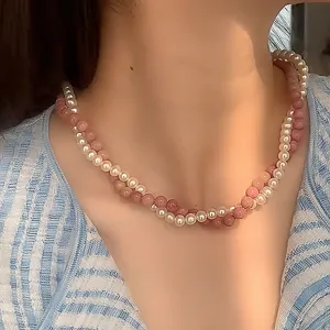 Primo piano di una collana a due strati con perle bianche e rosa su un collo
