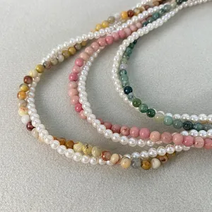 Dettaglio di collane con perle e pietre naturali multicolori su uno sfondo grigio