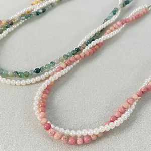 Dettaglio di una collana di perle a due strati con perle verdi e rosa, stile sovrapposto