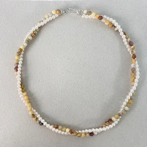 Vista dettagliata della collana a doppio filo intrecciato con perle bianche e pietre