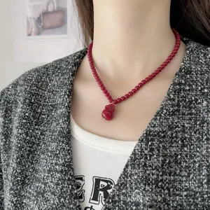 Primer plano de un collar festivo de cuentas rojas con un colgante de la suerte.