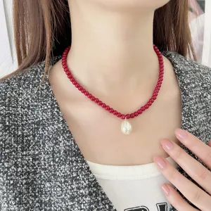 Elegante collar de cuentas rojas con colgante de perla en gota, lucido por modelo
