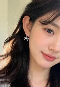 Close-up of exquisite silver bow knot earrings with sparkling cubic zirconia on model