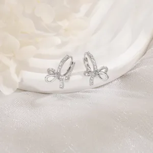 Detailed view of silver-tone bow hoop earrings adorned with sparkling zirconia stones.