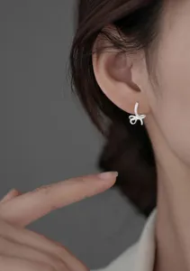 Close-up of sparkling cubic zirconia bow earrings worn on an Asian model's ear